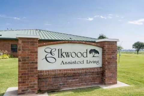 Outdoor brick sign for Elkwood Assisted Living on a green lawn.