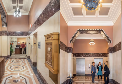 Two views of an elegant lobby area with marble floors and walls, decorative ceiling moldings, and hanging light fixtures. The left image shows a hallway with a vintage mailbox and a reception desk with two people standing. The right image shows three women talking near two elevator doors under a decorative archway.