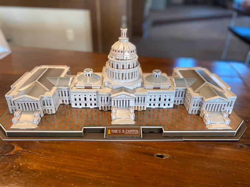 A detailed scale model of the U.S. Capitol displayed on a wooden table indoors.