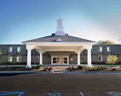 Front view of Rivergate Health Care Center with a portico entrance and parking.