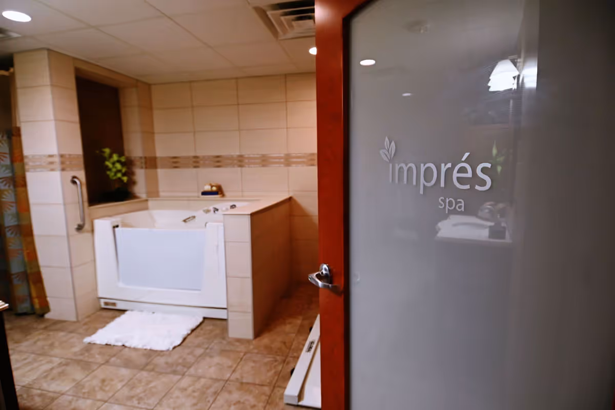 Tiled spa bathroom with a walk-in bathtub and a frosted glass door labeled "imprés spa".