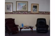 Small sitting area with two armchairs, a coffee table and framed pictures on the wall.