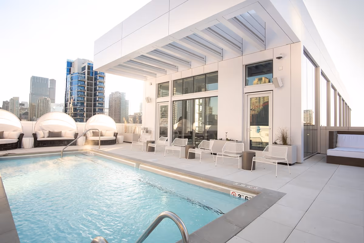 Rooftop pool and lounge area with modern seating and a city skyline in the background.