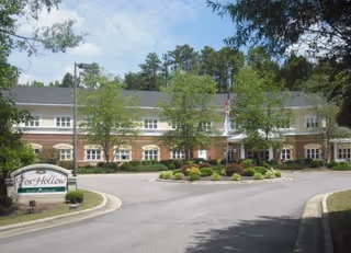 Front entrance of Fox Hollow Senior Living Community showing the building facade, circular driveway, sign, and landscaped grounds.