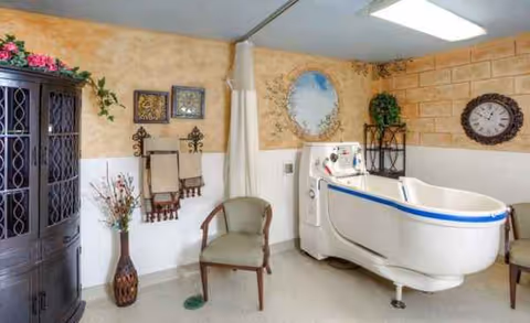 Interior room in a senior facility featuring a large white hydrotherapy tub and chairs.