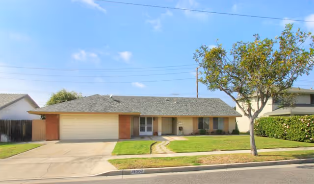 Front exterior view of a single-story home with garage and lawn.
