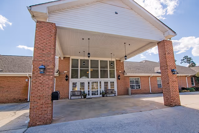 Brick entrance with a covered porte-cochere and glass doors at Monarch Place.