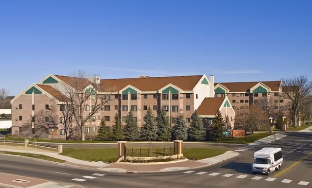Exterior view of Copperfield Hill senior living building with trees and road in front.