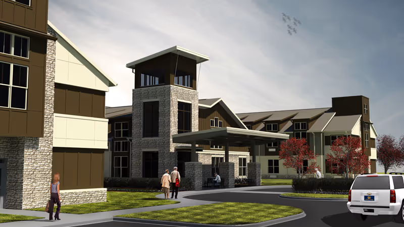 Exterior view of a senior living facility with a modern design featuring stone and brown paneling. The building has a covered entrance with a tower-like structure. Several people are walking near the entrance, and a white SUV is parked on the driveway. Trees with red leaves and a partly cloudy sky with a formation of birds flying are visible in the background.