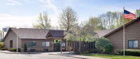 Front exterior of Chalet Rehabilitation and Healthcare Center with flag and trees.