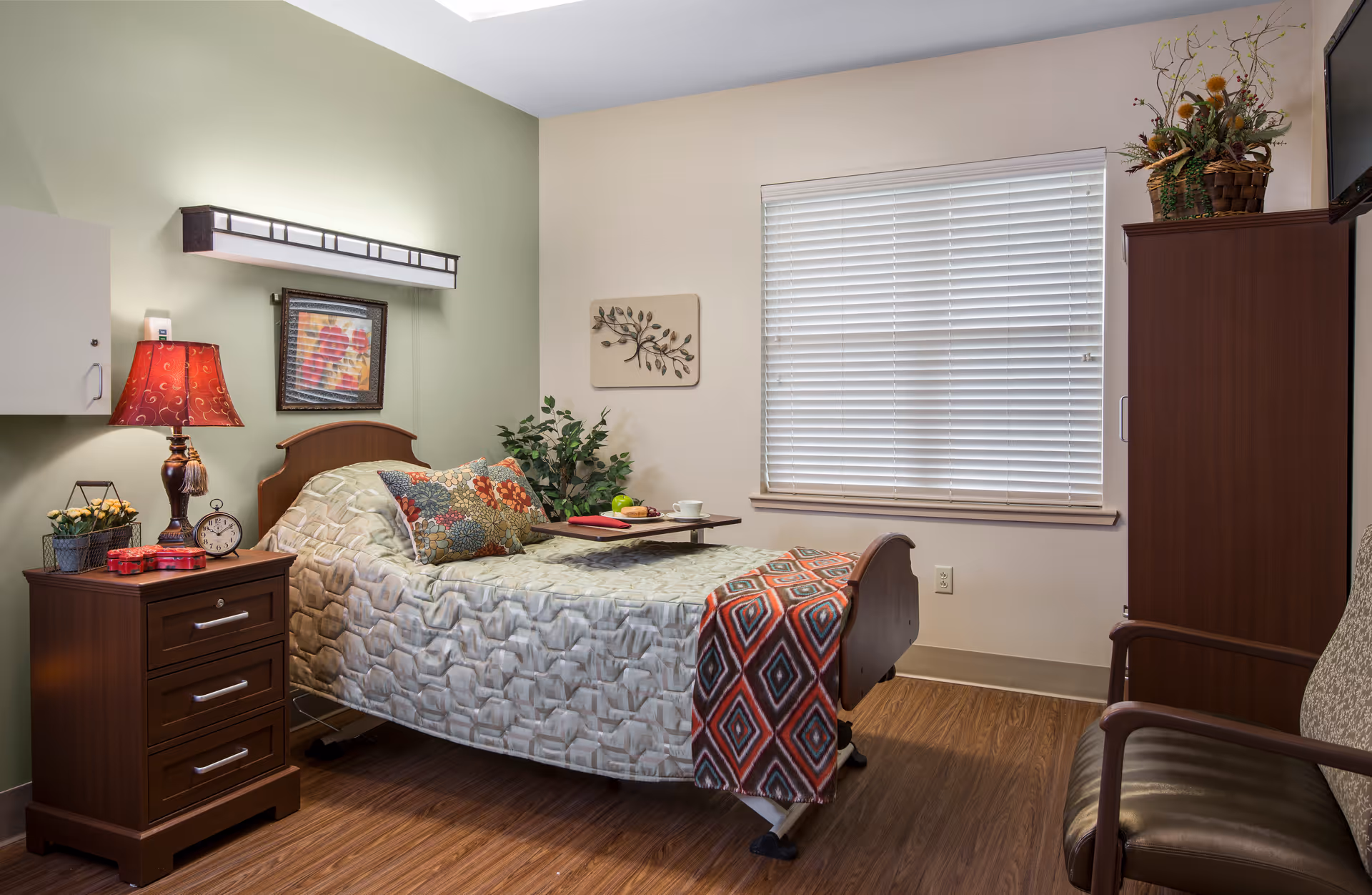 Furnished private bedroom with a single bed, nightstand and lamp, armchair, wardrobe, and a window with blinds.