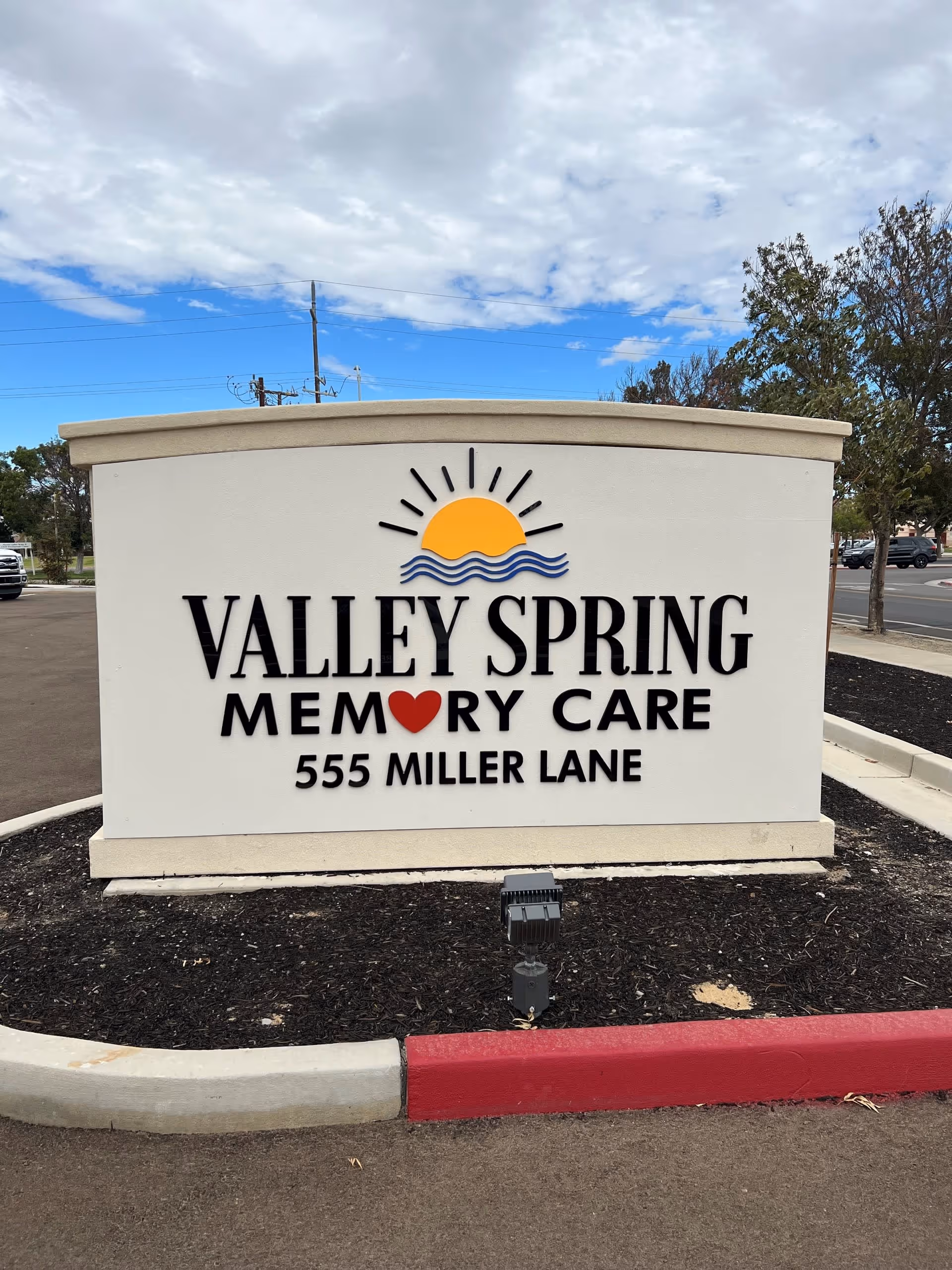 Outdoor sign for Valley Spring Memory Care located at 555 Miller Lane, featuring a sun and waves logo above the text.