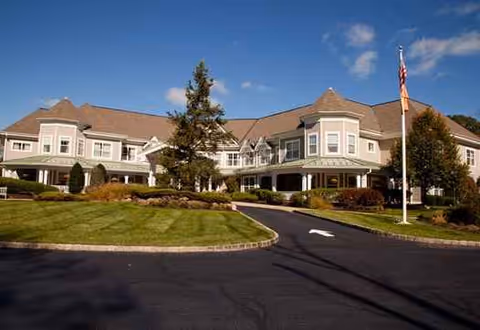 Two-story senior living facility with a circular driveway and manicured lawn, Sunrise at West Essex.
