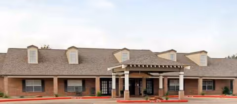 Brick senior living facility front with a covered entrance and parking area.