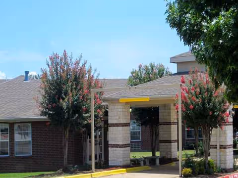 Exterior view of North Pointe Nursing & Rehabilitation entrance with trees and brick facade.