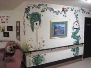 Interior hallway with wall mural, framed art, handrails, and pink seating.