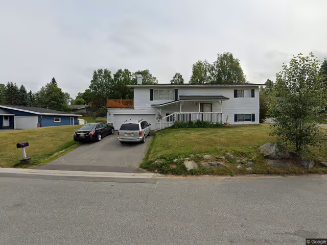 Front view of a two-story white suburban house with a driveway and two cars parked in front.