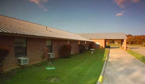 Franklin Nursing Home exterior: single-story brick building, covered entrance, walkway, and manicured lawn.