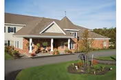 Front view of a brick memory care facility with a covered entrance and landscaped lawn.
