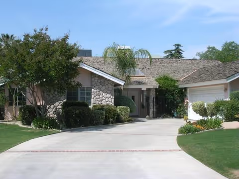 Single-story senior living facility with stone facade, driveway, and landscaped entrance.