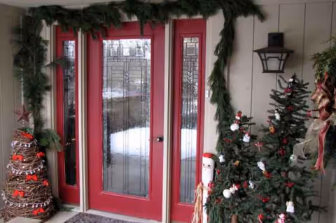 Entrance of Tanglewood Assisted Living with red doors, garlands, and Christmas trees.