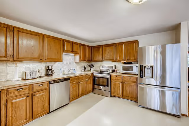 Spacious kitchen with wooden cabinets and stainless steel appliances including a refrigerator, oven, dishwasher, and microwave.