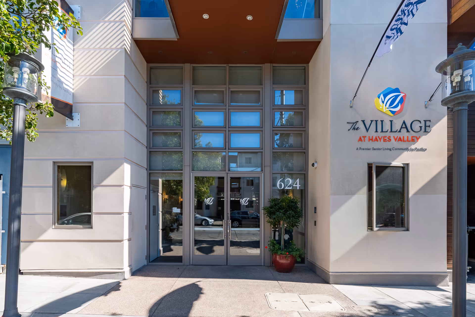 Front entrance of The Village at Hayes Valley senior living building with glass double doors, address number 624, and signage on the facade.