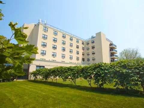 Exterior view of Rockaway Care Center with a multi-story building and green lawn.
