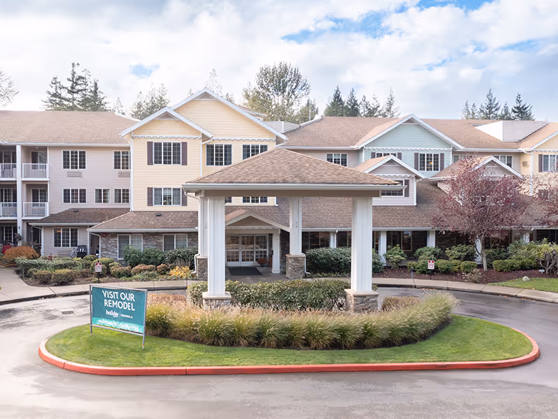 Exterior view of a multi-building senior living facility with a covered entrance and manicured landscaping.