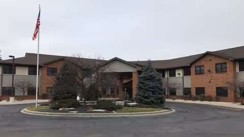 St Francis Terrace exterior with flag, circular driveway, and landscaped entrance.