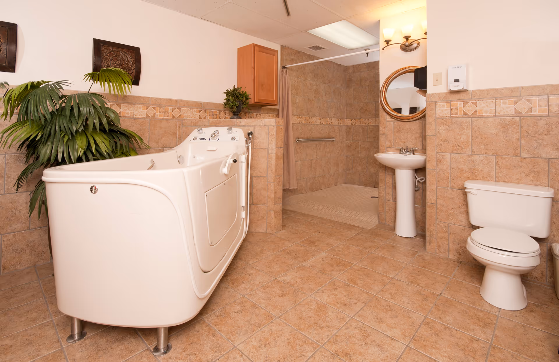 Spacious tiled bathroom with a walk-in tub, roll-in shower, pedestal sink, toilet, and potted plant.