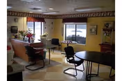 Communal dining area with round tables and chairs, a service counter with floral arrangements, and windows showing snow outside.
