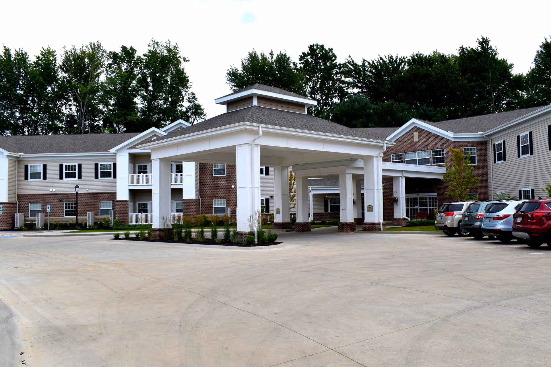 Exterior view of Danbury Mentor senior living facility with a covered entrance and parking.