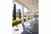 Front porch of Merry Wood Lodge with rocking chairs and American flags.