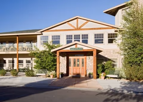 Main entrance of a senior living community with greenery and a welcoming doorway.