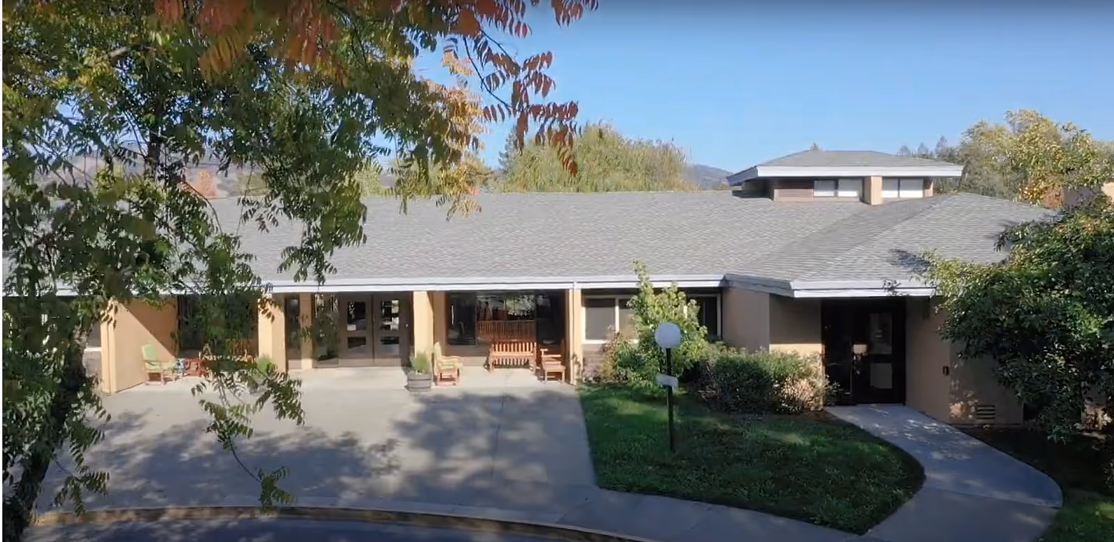 Front entrance of Friends House with a covered walkway, benches, and surrounding trees and landscaping.