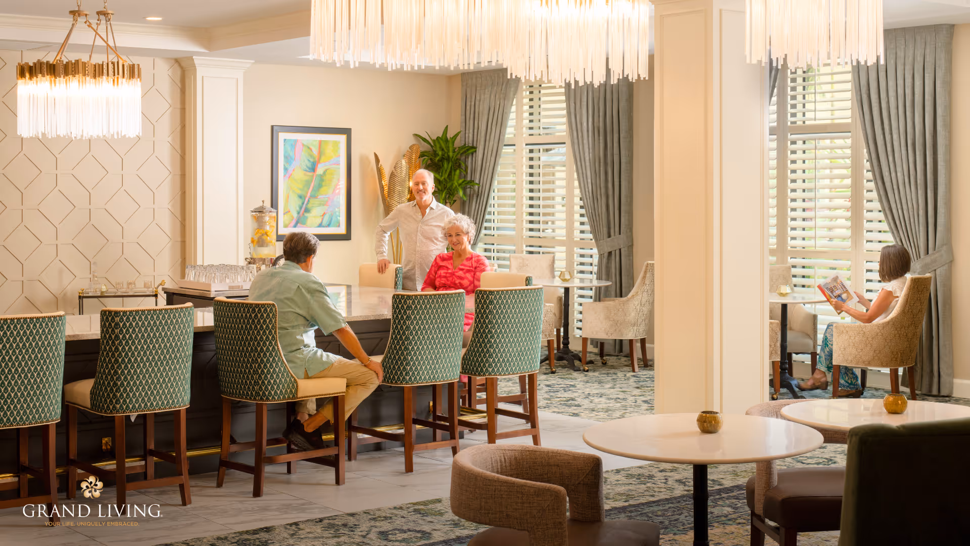 Bright, elegant senior living common area with a bar, tables, chandeliers, and residents socializing.