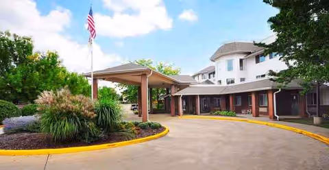 Solstice Senior Living Joliet exterior with curved driveway, flagpole, and covered entrance.