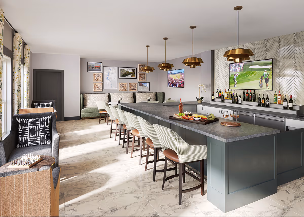 Bright communal bar and lounge with a long island lined with bar stools, pendant lights, seating areas, wall-mounted TVs and a stocked bar.