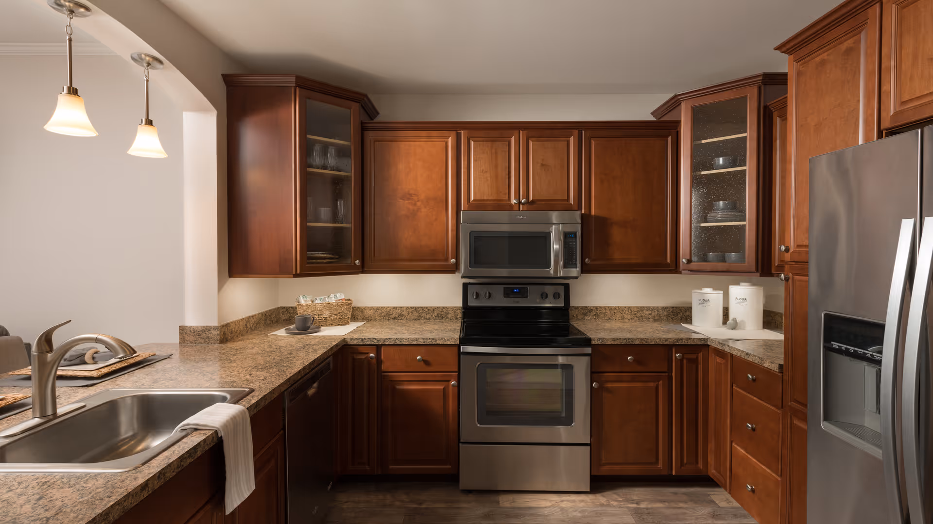 Modern kitchen with wooden cabinets, stainless steel appliances, granite countertops, a sink, and pendant lights.