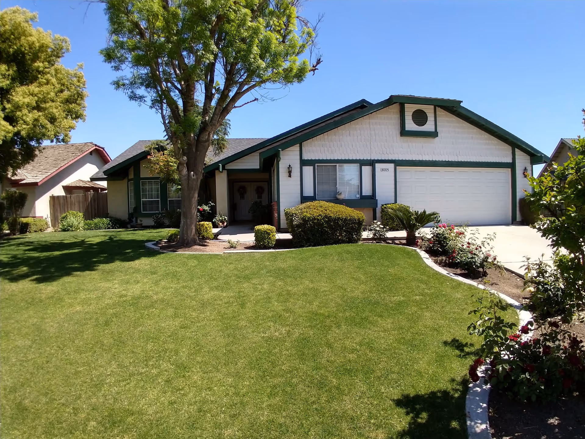 Single-story suburban house with an attached two-car garage, a large front lawn and a tree.