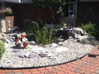 Brick building with a landscaped rock garden and decorative statues in front.