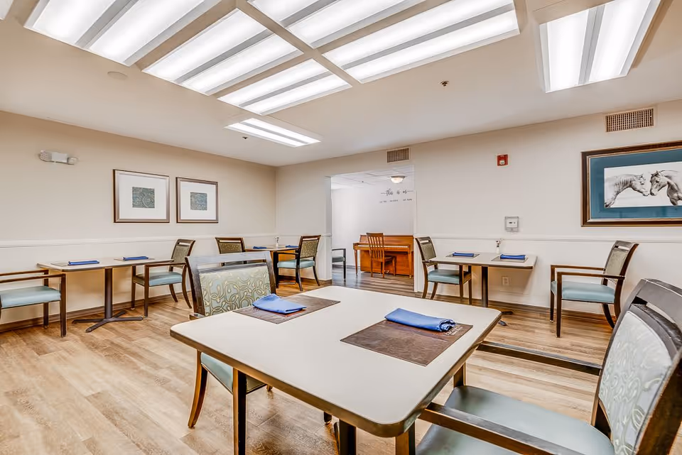 Well-lit dining room with tables and chairs set with placemats and folded napkins.