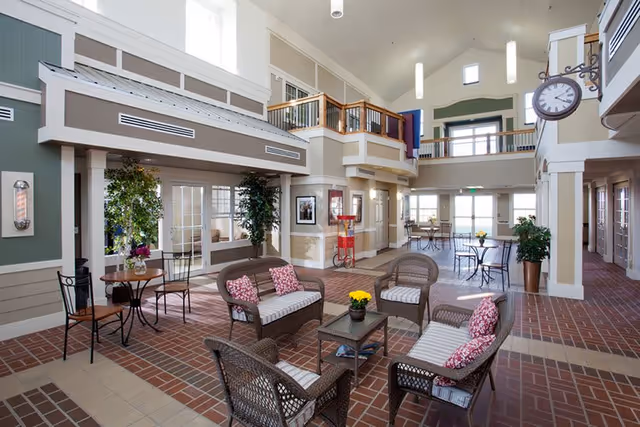 Spacious two-story communal lounge with wicker seating, small tables, high ceilings, and an upper balcony.
