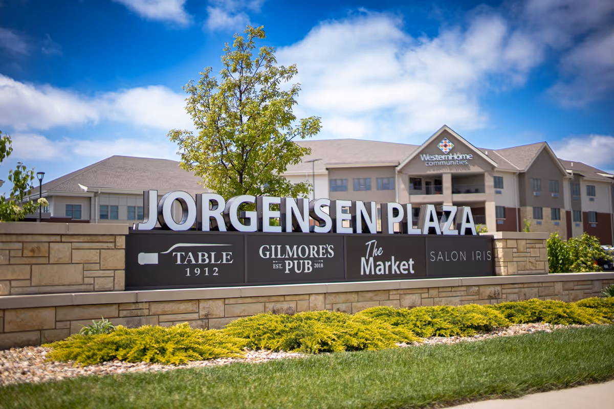 Outdoor view of a large Jorgensen Plaza sign in front of a Western Home Communities building under a blue sky.