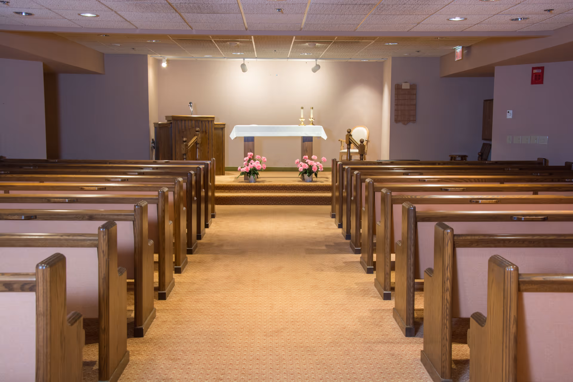Interior chapel with rows of wooden pews facing an altar adorned with flowers and candles.