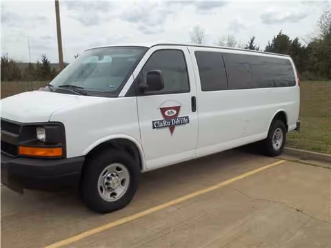 White ClaRu DeVille Nursing Center van parked in a lot with logo on the side.