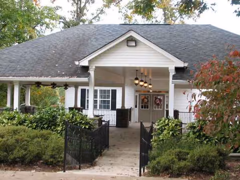 Covered entrance to Amberley Senior Community with path, greenery, and hanging lights.