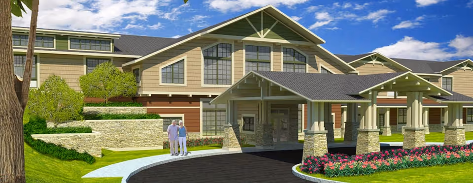 Exterior rendering of Traditions of Beavercreek showing the main entrance with a covered porte-cochere, landscaped flowerbeds, and two people on the walkway.