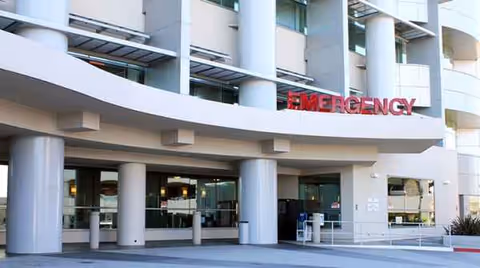Curved hospital entrance with glass doors and an Emergency sign